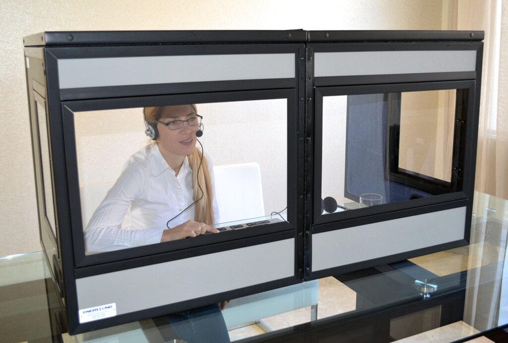 Interpreter working inside a tabletop interpreting booth with a console and headset