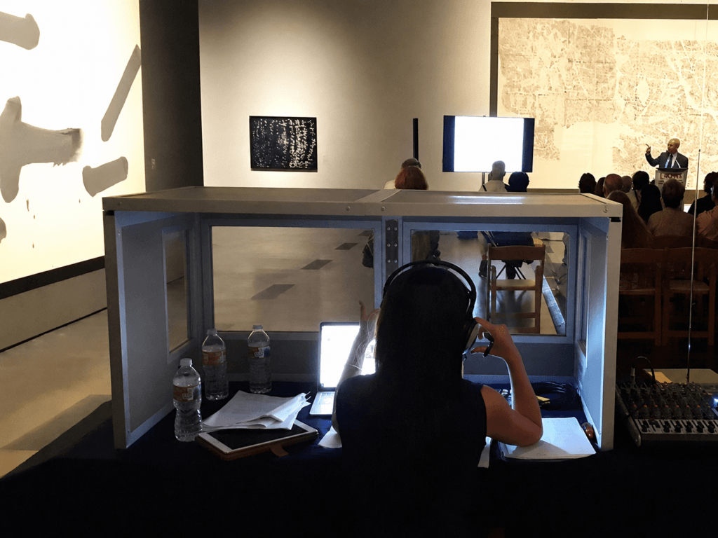 Tabletop interpreting booth set up on a table in a gallery, with the console and microphone inside