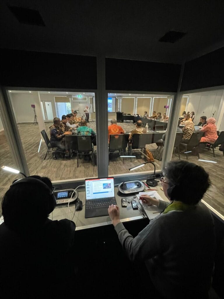 Interlingual interpreter working at an infrared console inside the booth during the Canberra programme