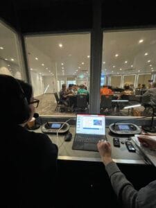 Interpreter at the booth console looking out at the delegation in session